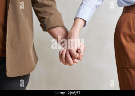 Mittellange Nahaufnahme eines nicht erkennbaren heterosexuellen jungen Mannes und einer verliebten Frau, die die Hände halten Stockfoto