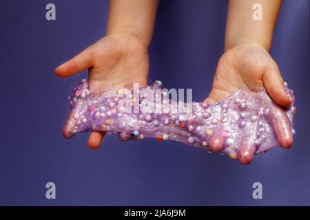 Schleim zu Hause machen. Kind hält und dehnt bunten Schleim. DIY-Konzept Stockfoto