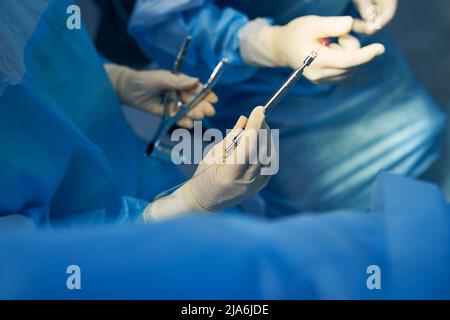 Krankenschwester, die elektrochirurgischen Bleistift an den Operationsarzt übergibt Stockfoto