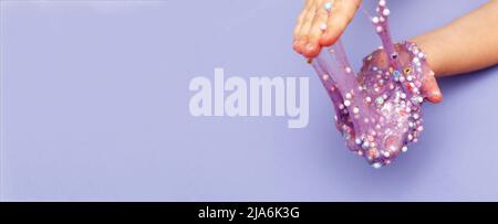 Schleim zu Hause machen. Kind hält und dehnt bunten Schleim. DIY-Konzept. Banner Stockfoto