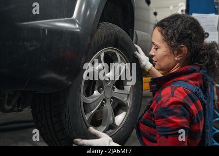 Frau Auto Mechaniker Überprüfung Autorad in Reparatur-Service-Station Stockfoto