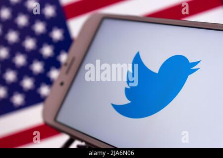 Kumamoto, Japan - Feb 16 2021 : Twitter-Logo auf dem iPhone auf US-Flagge. Twitter ist ein US-amerikanisches Microblogging und SNS, auf dem Nutzer Tweets posten und mit ihnen interagieren Stockfoto