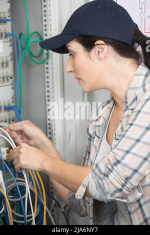 Frau, die Kabel in den Server anführt Stockfoto