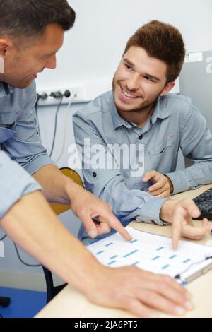 Zwei Männer sitzen am Telefon zusammen und lernen sprechen Stockfoto