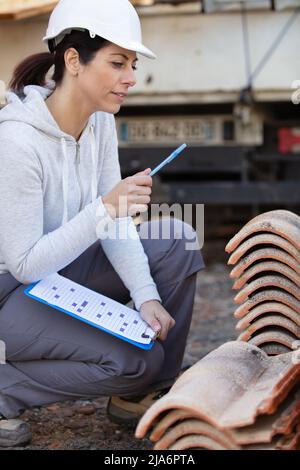 Lächelnde Maurerin, die eine neue Fliese legt Stockfoto