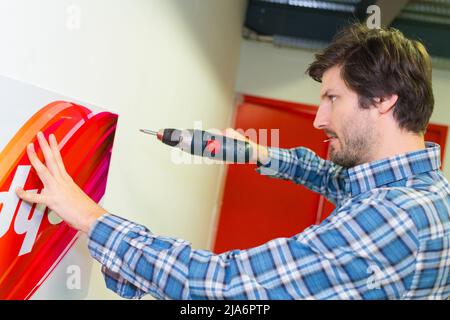 Mitte der erwachsene Mann bohren Loch in Wand Stockfoto