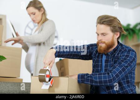 Mann versiegelt einen Versandkarton Stockfoto