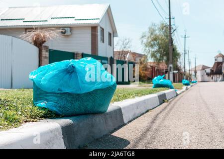 Ein Plastikmüllsack mit Abfall, der auf dem Bürgersteig eines Vororts liegt. Nahaufnahme. Konzept der kommunalen Reinigung Service. Stockfoto