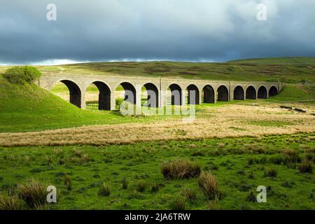 Der gewölbte Eisenbahnviadukt auf dem Gipfel von Garsdale in Cumbria an einem Sonnenschein-/Regennachmittag Stockfoto