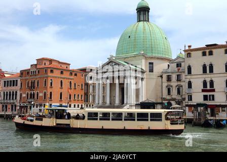 kirche, die dem Heiligen Simeon Piccolo auf der Insel Venedig in Italien in Europa gewidmet ist, und eine Fähre auf dem Wasser des Canale Grande Stockfoto