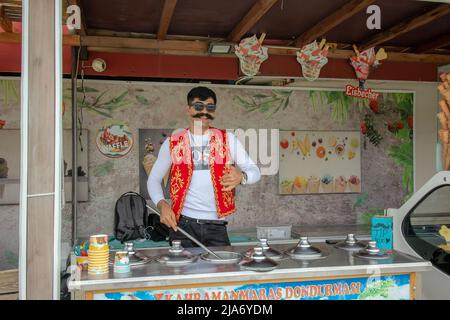 Der türkische Eisverkäufer in der Straße trägt traditionelle Kleidung und Schnurrbart. Stockfoto