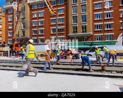 Paris, Frankreich, Group Foreign Construction Workers applying concrete to Tram Tracks on Street Stockfoto