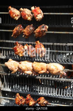 Rotisserie mit Spieß-gebratenen Hühnern und Schweineschinkenfleisch beim Kochen im Restaurant Stockfoto