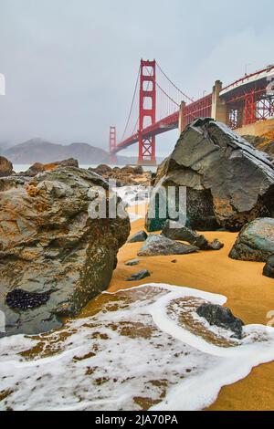 Nebliger Morgen an der Golden Gate Bridge von Sandstränden mit Meereswellen und Felsen Stockfoto