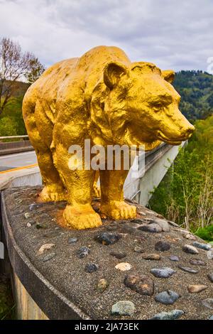 Große goldene Bärenstatue markiert den Eingang zur Brücke im Wald Stockfoto