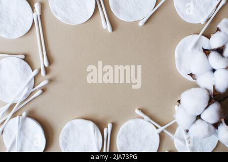 Flauschige Baumwollblumen-Wattestäbchen und Wattestäbchen auf beigem Hintergrund mit Platz zum Kopieren. Hygienisches Einwegprodukt Stockfoto