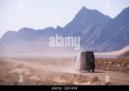 4x4 Camper van Foto von hinten auf einer staubigen Wüstenstraße im Iran aufgenommen Stockfoto