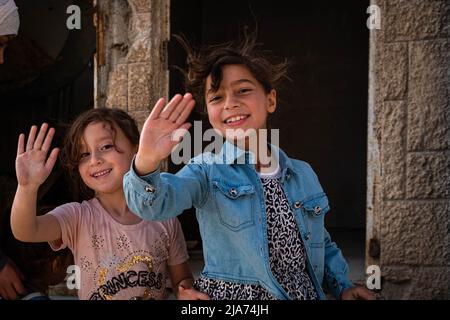 Syrische Kinder winken nach dem Bürgerkrieg in Darayya mit ihren Händen und lächeln. Stockfoto