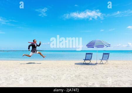 Glücklicher Geschäftsmann, der von der Arbeit am tropischen Strand läuft. Konzept für Sommerferien. Stockfoto
