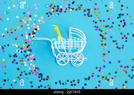 Ein Jahr Geburtstagsfeier .Baby Kinderwagen mit einer Kerze in Form der Nummer eins auf blauem Hintergrund mit Sternen Konfetti-Pailletten Stockfoto