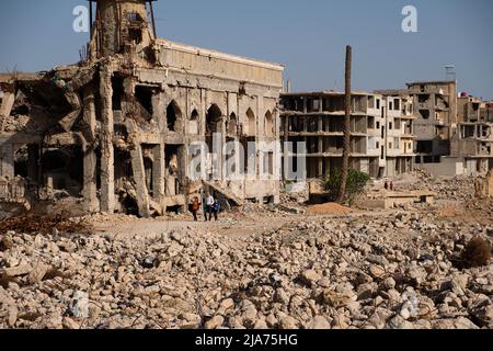 Darayya, Syrien - April, 2022: Eine Familie, die nach dem syrischen Bürgerkrieg durch Ruinen in der zerstörten Stadt geht. Stockfoto