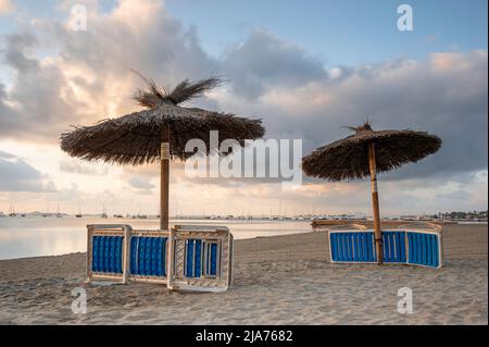Liegen und Sonnenschirme, an einem spanischen Strand, für den Abend abgestellt Stockfoto