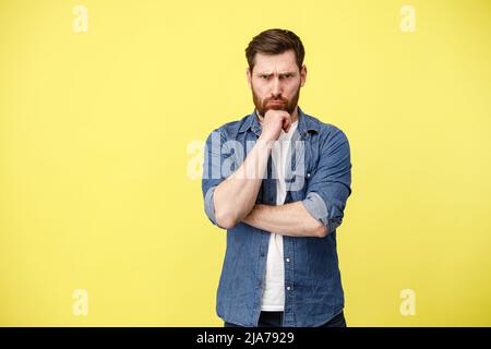 Ernsthafter Mann hält die Hand auf gelbem Grund in der Nähe des Bartes Stockfoto