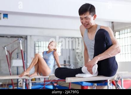 Paar sitzen auf parallelen Balken Stockfoto