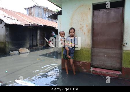 Sylhet, Bangladesch. 24.. Mai 2022. Ein kleines Mädchen mit ihrer Schwester auf dem Schoß, die in schmutzigem Wasser steht, während sie in ein Nachbarhaus in Sylhet, Bangladesch, umzieht.das Sturzflutwasser dringt durch den Anstieg des Wasserpegels in den Flüssen Surma und Kushiyara in die Häuser der Stadt Sylhet ein. (Bild: © Pinu Rahman/Pacific Press via ZUMA Press Wire) Stockfoto