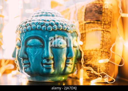 Blaue Statue des Buddha-Kopfes, beleuchtet von Bokeh-Bokelichtern. Innenelement Stockfoto