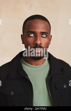 Porträt eines ernsthaften jungen afroamerikanischen Mannes mit Halloween-Linsen in schwarzer Jacke Stockfoto