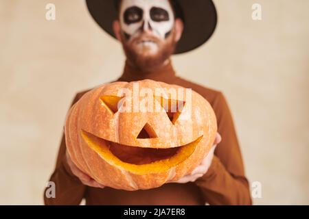 Nahaufnahme eines bärtigen Mannes im Hexer-Kostüm mit handgefertigter Jack-o-Laterne, Halloween-Konzept Stockfoto