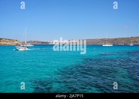 COMINO, MALTA am 2022. Mai: Boote auf blauer Lagune auf europäischer Insel, klarer blauer Himmel an warmen sonnigen Frühlingstag. Stockfoto
