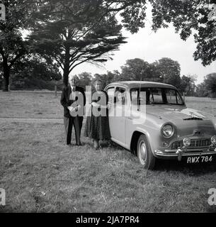 1950s, historisch, nach dem Krieg Großbritannien und auf Parkland, ein älteres Paar, das stolz für ein Foto stand, von ihrem neuen Auto der Ära, einem Austin A40 Cambridge. Der vom britischen Hersteller Austin Motor Company hergestellte Austin Cambridge wurde von 1954 bis 1971 in verschiedenen Versionen und Karosserieformen produziert. Stockfoto