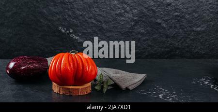 Frische Tomate und Aubergine von Raf Coeur De Boeuf mit Orangen auf grauem Hintergrund, Textil, Restaurantkonzept, Stockfoto Stockfoto