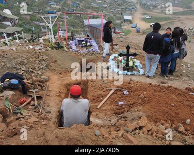 Mann, der in einem Grab sitzt. Der Friedhof von La Esperanza, im Stadtteil Villa el Salvador in Lima, ist einer der größten in ganz Amerika und empfängt fast zwei Millionen Besucher pro Jahr, nur am Tag der Toten. Stockfoto