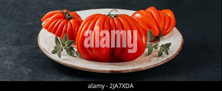 Raf Coeur De Boeuf in Scheiben geschnitten, Rindertomaten mit Orang auf weißem Teller, grauer Hintergrund, Restaurantkonzept, Stockfoto Stockfoto