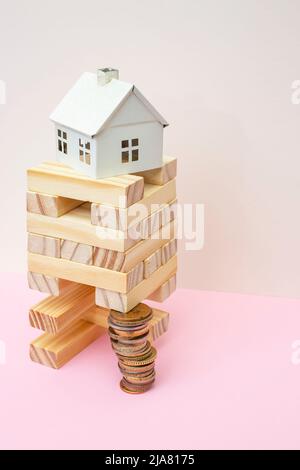 Holzblöcke Turm von einem Stapel von Münzen unterstützt. Konzept der Fundamentkosten. Stockfoto