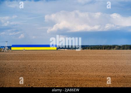 Auf Ackerland Feld ein großer Hangar von gelbblauer Farbe Stockfoto