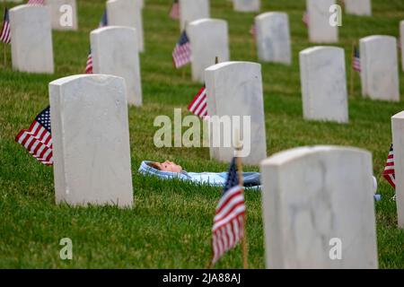Los Angeles, Kalifornien, USA. 28.. Mai 2022. Ein Junge ruht zwischen den Grabsteinen, nachdem am Samstag, den 28. Mai 2022, Tausende US-Flaggen auf dem Nationalfriedhof von Los Angeles für die Feierlichkeiten zum Memorial Day in Los Angeles aufgestellt wurden. (Bild: © Ringo Chiu/ZUMA Press Wire) Stockfoto
