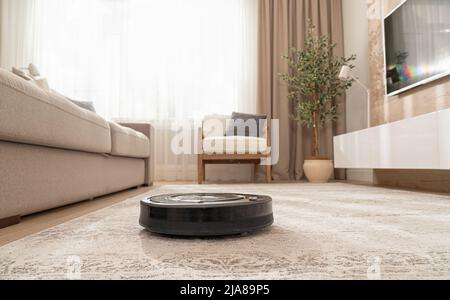 Reinigung des Teppichs in einer modernen Wohnung mit einem Staubsaugerroboter Stockfoto