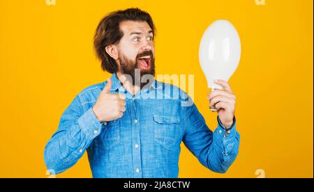 Gute Idee. Glücklicher bärtiger Mann mit Glühbirne und Daumen nach oben. Inspiration, Kreativität, Innovation. Stockfoto