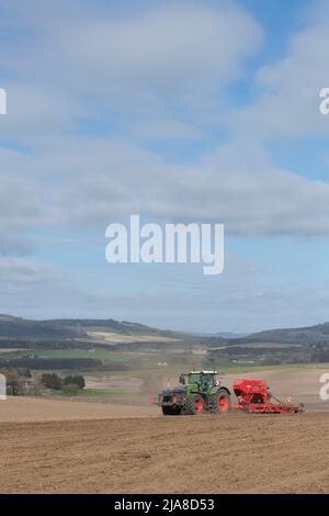 Ein grüner Fendt-Traktor und eine rote Horsch-Sämaschine säen im Frühjahr ein gepflügtes Feld mit Blick auf eine landschaftlich reizende Farmlandschaft in Aberdeenshire Stockfoto