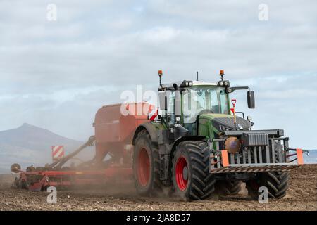 Ein grüner Fendt-Traktor und ein roter Horsch-Scheibensaatbohrer säen Gerste auf einem Trockenpflügefeld in Sichtweite von Bennachie in Aberdeenshire, Schottland Stockfoto