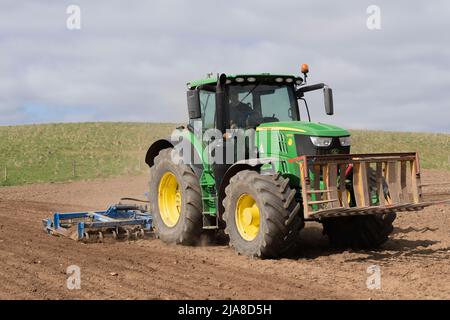 Ein John Deere 6175 R-Traktor, der einen Scherklaufer auf einem gepflügten Feld schleppt, als Vorbereitung für die Aussaat einer Gerstenfrucht Stockfoto