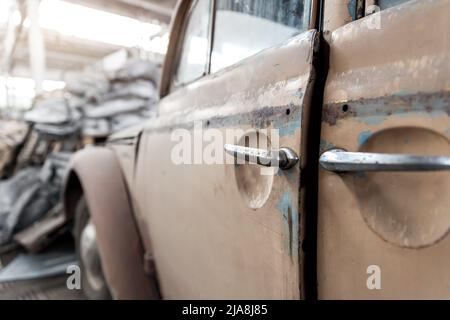 Nahaufnahme Detail rostig verlassene antike Oldtimer alten Autogriff Schrottplatz Fabrik Lagerhaus drinnen. Klassische Oldtimer-Retro-Fahrzeuge Stockfoto