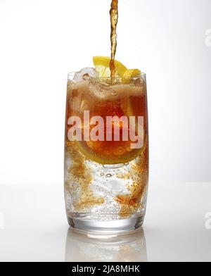 cola ergießt sich in ein Cocktailglas auf weißem Hintergrund Stockfoto
