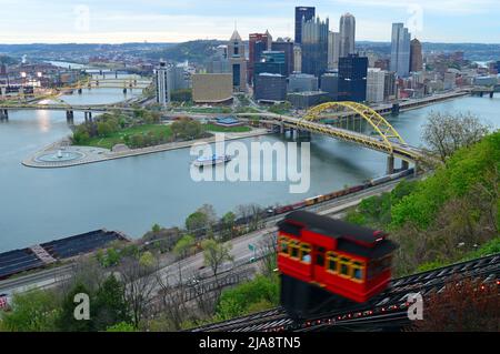 Die Seilbahn steigt auf einen Hügel mit der Skyline von Pittsburgh dahinter. Stockfoto