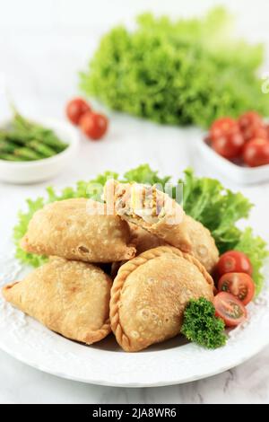 Kue Pastel oder Jalangkote, beliebtes Gericht aus Südostasien als Curry-Puff. Dieser Snack mit Reisnudeln, Karotten, Kartoffeln gefüllt und mit Gree serviert Stockfoto