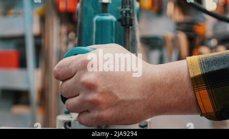 Zimmerei im Innenbereich - ein Holzarbeiter poliert das Holzdetail von oben in der Werkstatt - hält die Poliermaschine Stockfoto